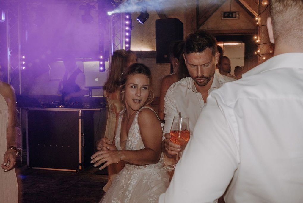 Eine feiernde Gruppe mit fröhlichen Menschen auf der Tanzfläche und buntem Licht.