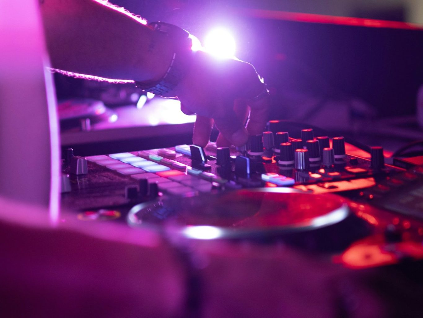 DJ-Service DJ bedient ein Deck mit bunten Lichtern im Hintergrund.