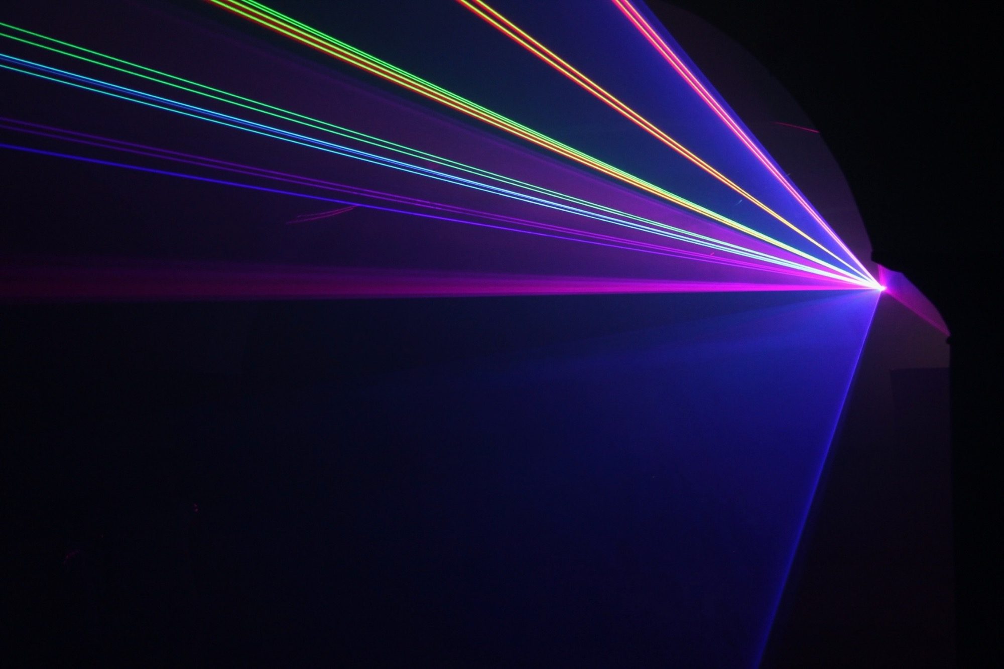 Bunte Lichtstrahlen strahlen diagonal auf dunklem Hintergrund.