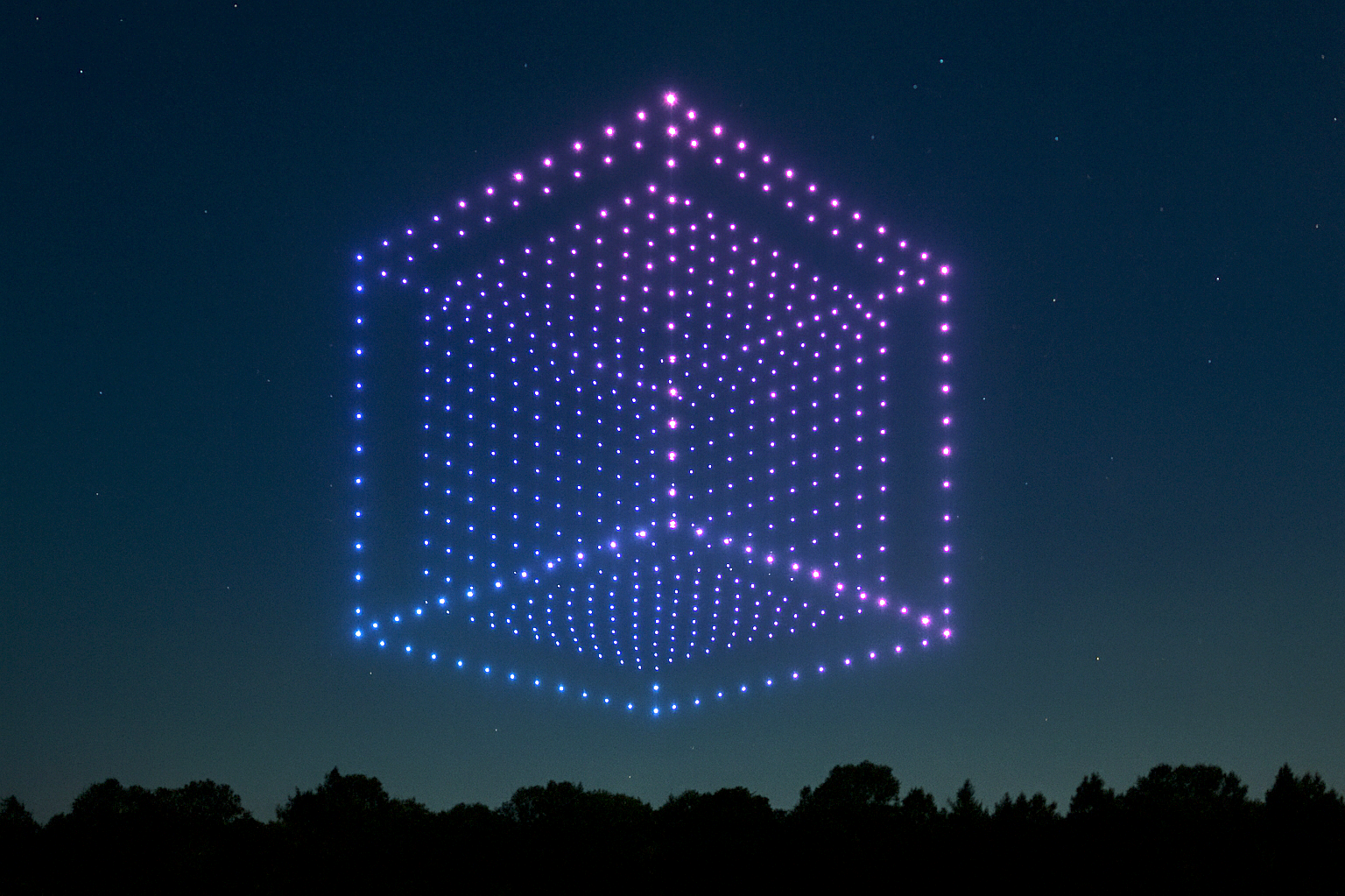 Abstrakte 3D-Würfelstruktur aus pinken und blauen Punkten vor einem nächtlichen Himmel.